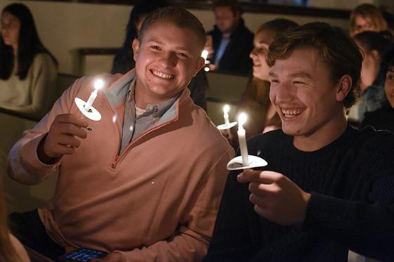 图为两名波胆网站的学生手持蜡烛，微笑着参加校园内的烛光礼拜. 