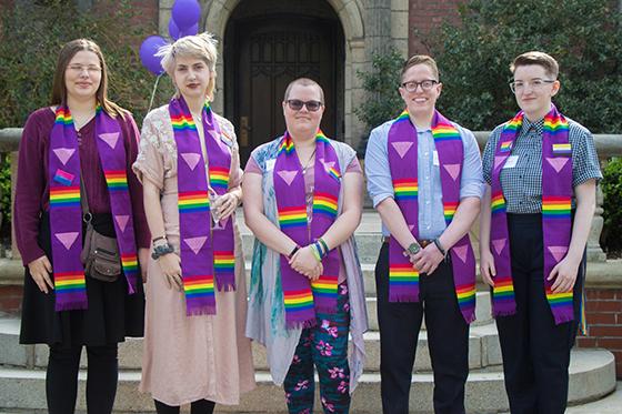 图为一群英国波胆网站的学生穿着印有彩虹LGBTQ+图案的毕业礼服, 一起摆姿势拍照. 